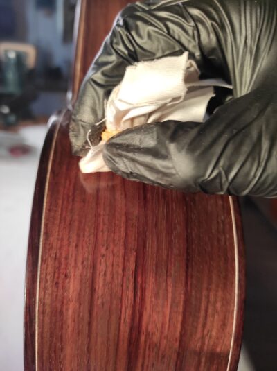 Luthier French polishing a guitar with a 