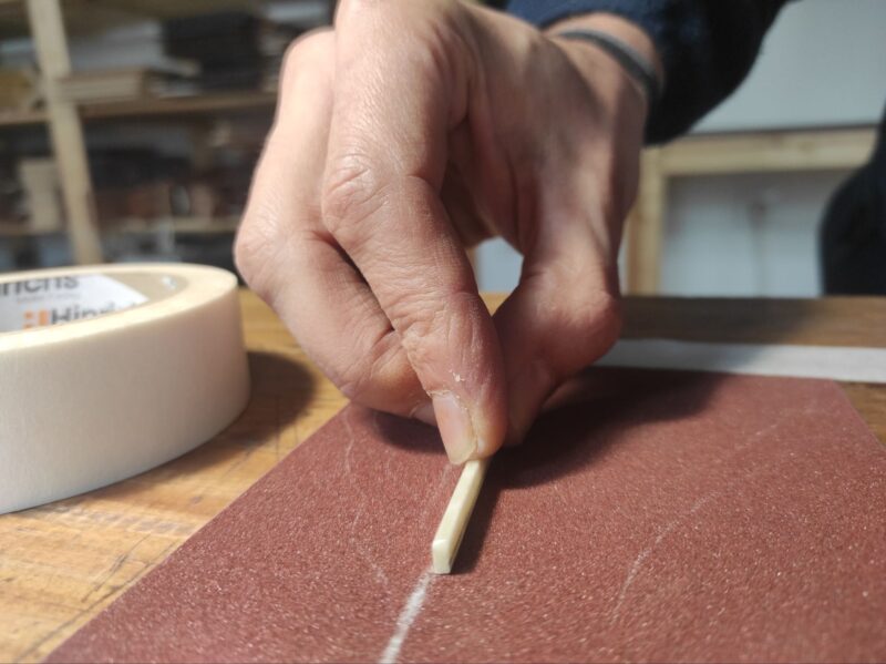 Sanding a guitar saddle for lowering the strings' action